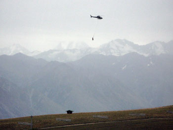 A helicopter carries in equipment for the construction of the lift line