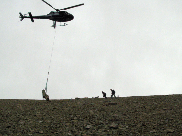 A helicopter lifts equipment for the lift to the construction team working on the lift line